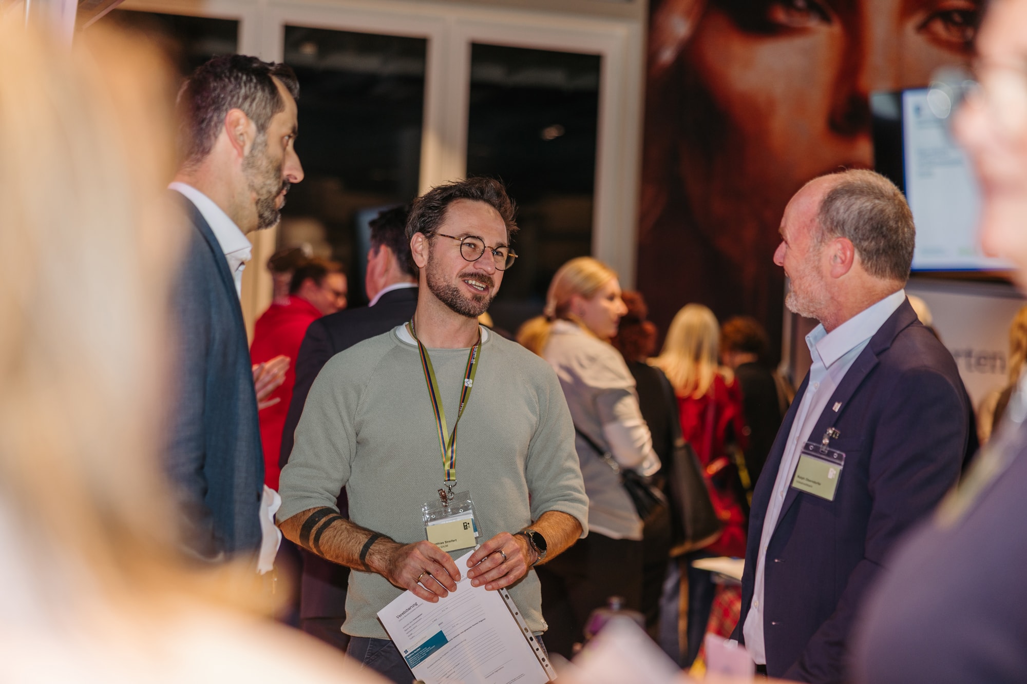 Collage aus drei Fotos: Links oben rollt eine Person Teig aus, links unten werden Kekse auf ein Blech gelegt, rechts stehen zwei Frauen in einer Werkstatt zwischen Maschinen und Holzkisten.